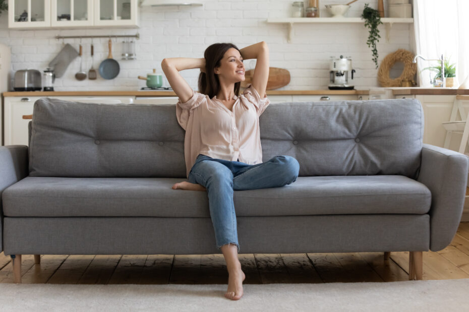 a young woman sittingon a grey sofa smiling in a cozy room in bulgaria sunny beach