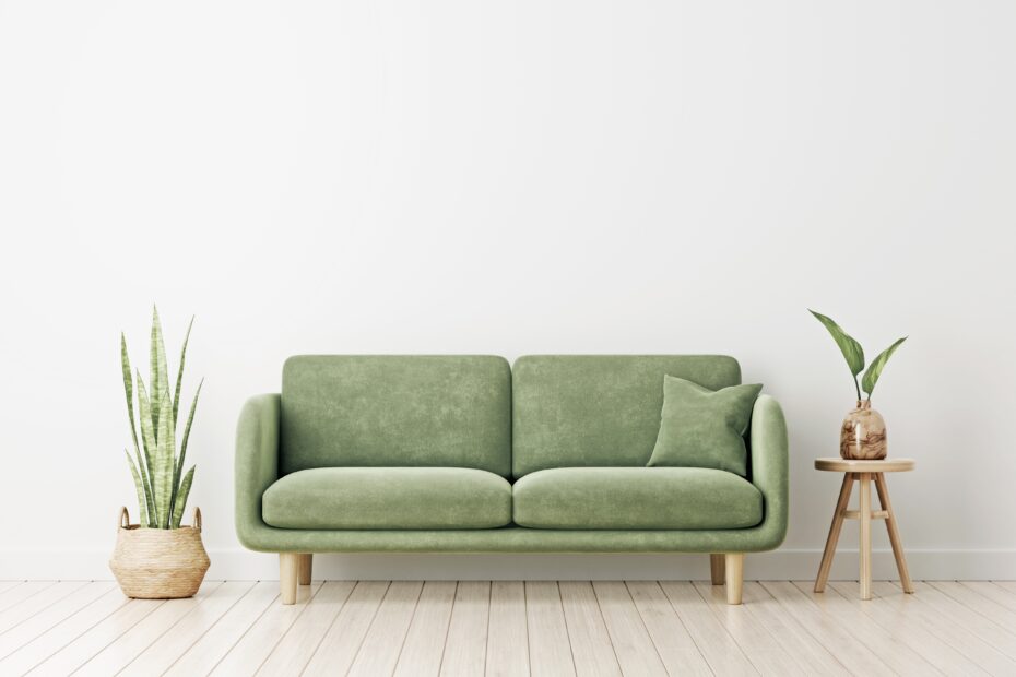 a beautiful green sofa placed in a greige painted room with plants on both side